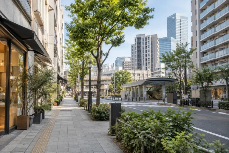 綠樹人行道、車站入口與城市公寓街景，AI 生成示意圖